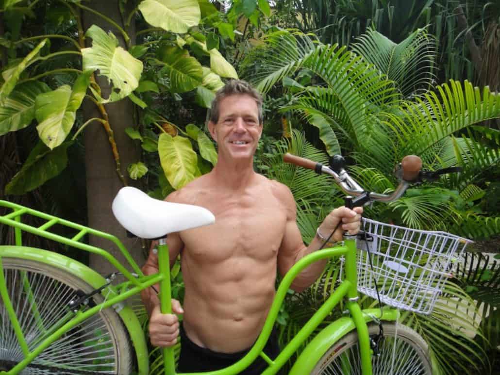 Ian, owner of Playa Bike Rentals, holding a green beach cruiser in Playa del Carmen